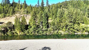 A gravel beach with a lake surrounded by dense forest. - Large Cabin on Ave of Giants with private Eel River access (Miranda)