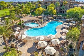 Ein Resort mit großem Schwimmbad, Liegestühlen und Sonnenschirmen.