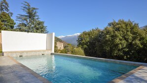 A swimming pool with clear blue water, surrounded by trees and a mountain in the background. - Stunning home in Vero with private swimming pool, can be inside or outside (Vero)