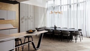 Une cuisine moderne dotée d’un îlot central, d’un coin repas avec une table ronde et d’une grande fenêtre agrémentée de rideaux légers.