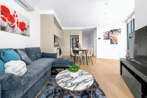 A modern living room with a grey sofa, a marble coffee table, and a flat-screen TV. - Early check in | Pool, Spa & Sauna | Centralised (Docklands)