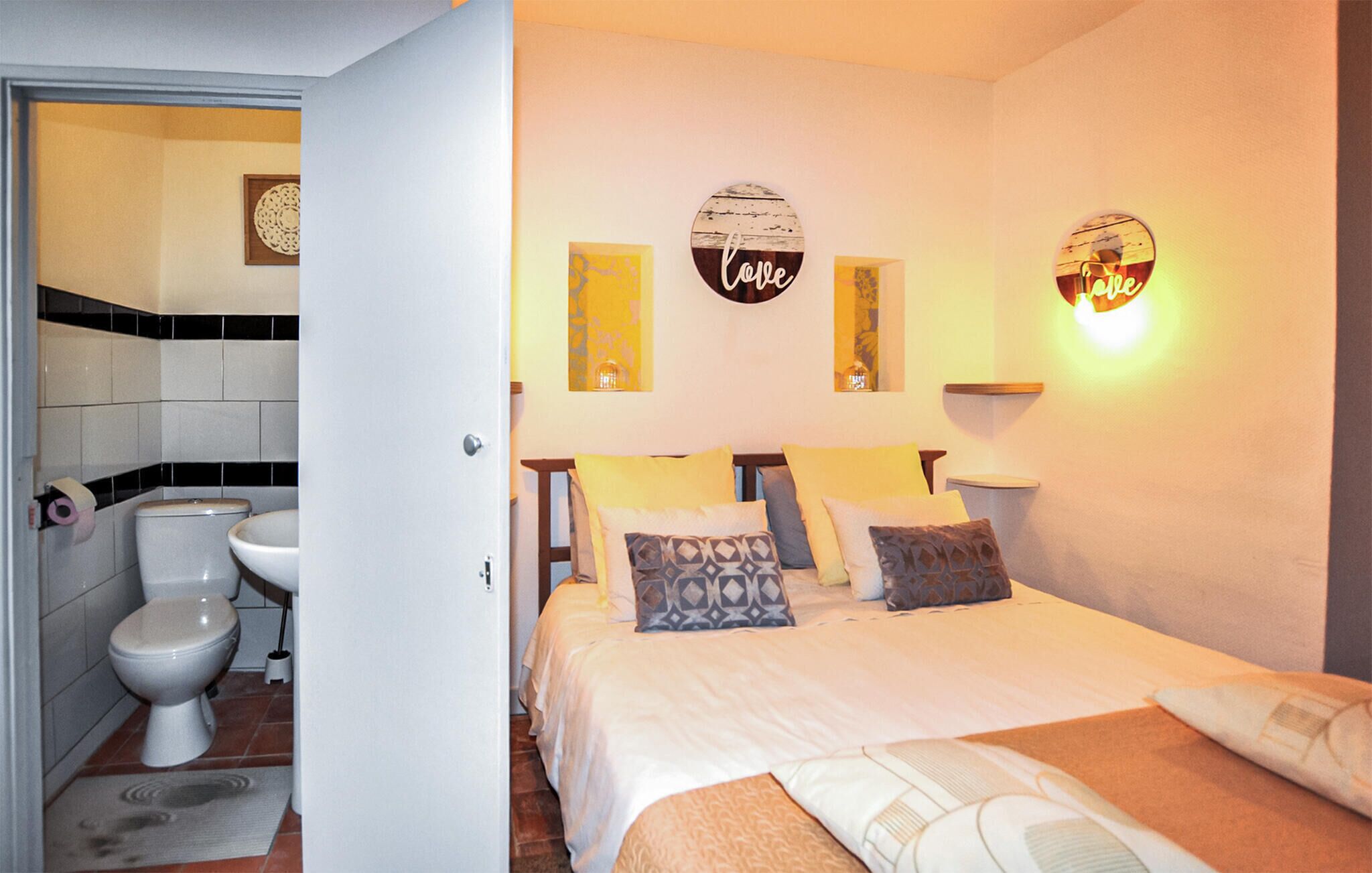 Een slaapkamer met een bed, twee nachtkastjes, een wandlamp en een wanddecoratie met de tekst 'love'.