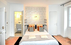 Camera d'albergo con un letto, un muro in pietra, un bagno e una porta.