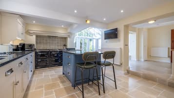 A spacious kitchen with a large island, built-in oven, and a TV mounted on the wall.