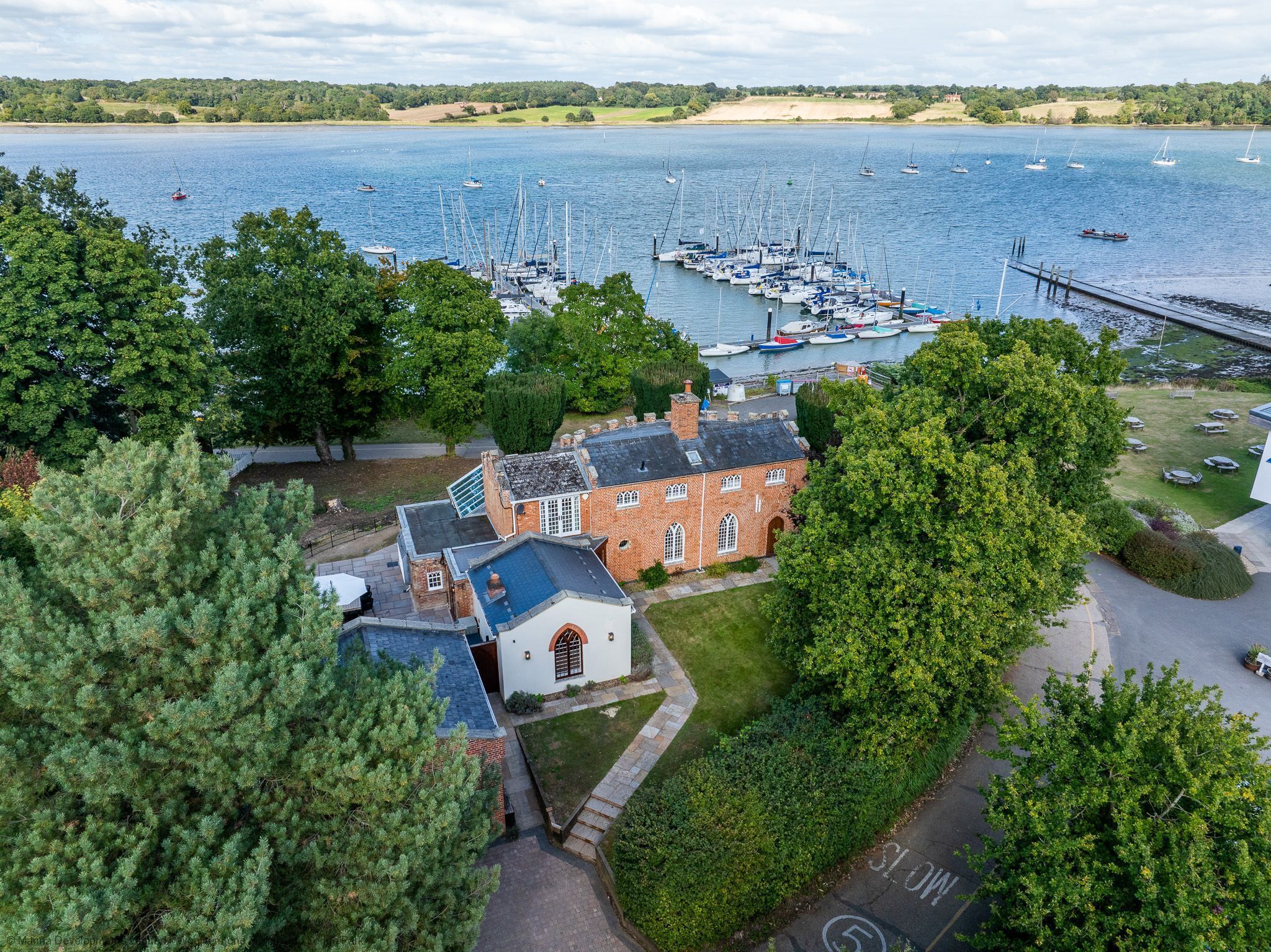 A coastal property with a marina, a brick building, and surrounding greenery.