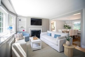 A modern living room with a fireplace, white sofas, and a television. - Family Cottage with 4 King Beds  (Norwalk)