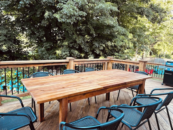 A wooden deck with a table and chairs, surrounded by a metal railing. - Family Cottage with 4 King Beds  (Norwalk)