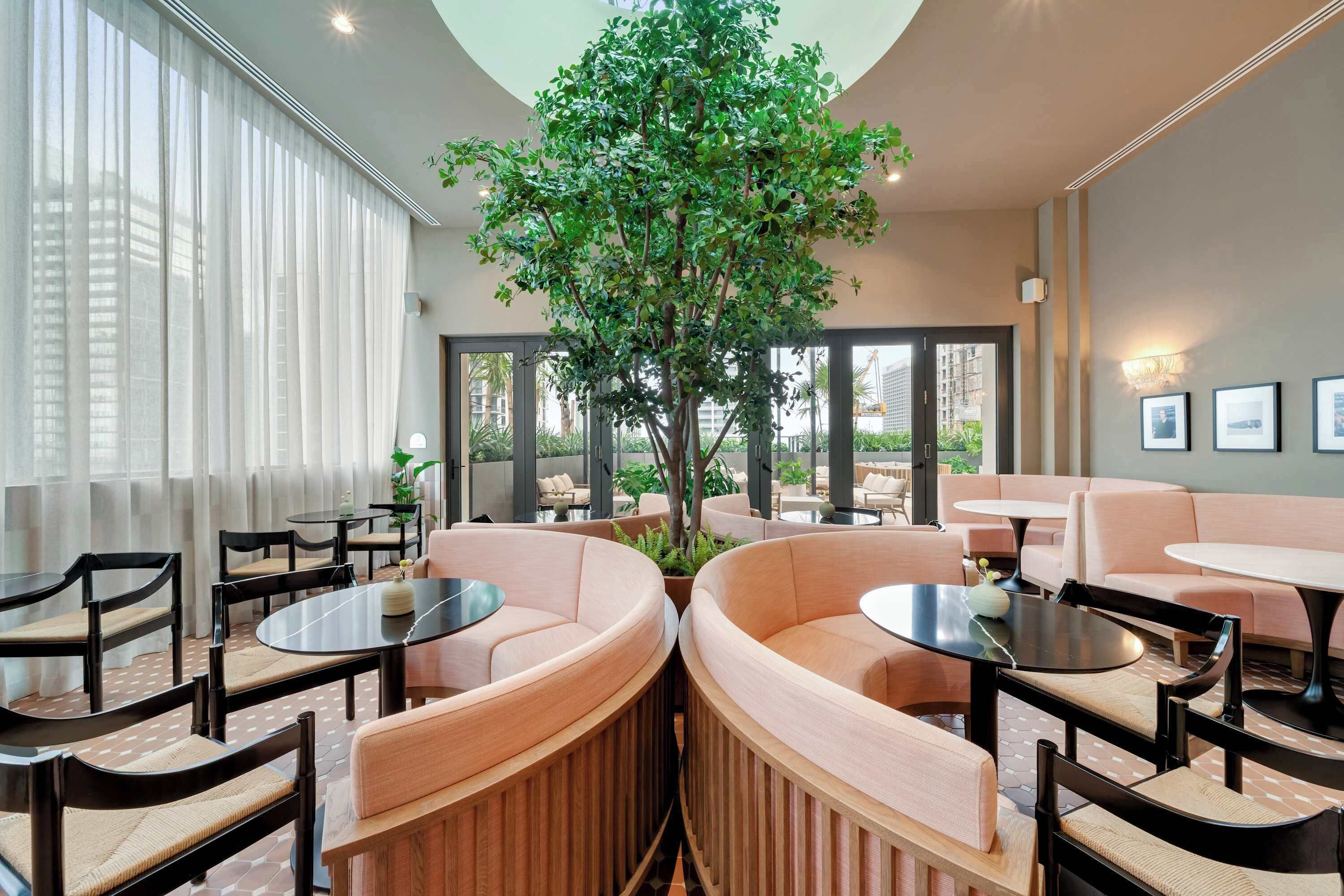 Un espace de détente moderne avec des sièges ronds, un arbre central et de grandes fenêtres.