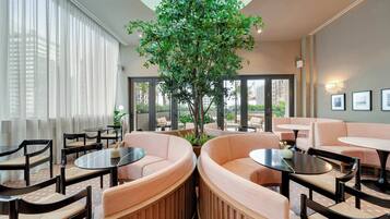 Un espace de détente moderne avec des sièges ronds, un arbre central et de grandes fenêtres.