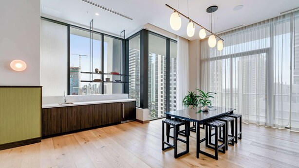 Eine moderne Küche mit großem Fenster, Holzboden und einem Essbereich mit Tisch und Stühlen.