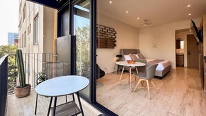 A modern apartment with a balcony, a dining area, a living room with a sofa and a bed, and a kitchen visible through an open door. - Mi Zona Lodging Chapultepec (Mexico City)