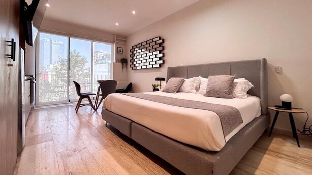 A modern bedroom with a large bed, a desk, and a chair. - Mi Zona Lodging Chapultepec (Mexico City)