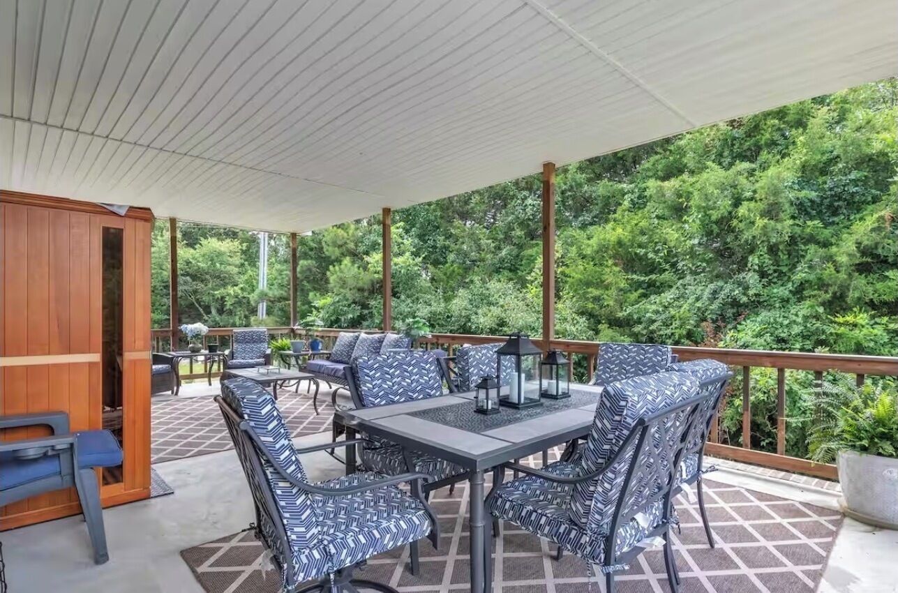 Une terrasse extérieure dotée d’un espace salon abrité, d’une table et de chaises.