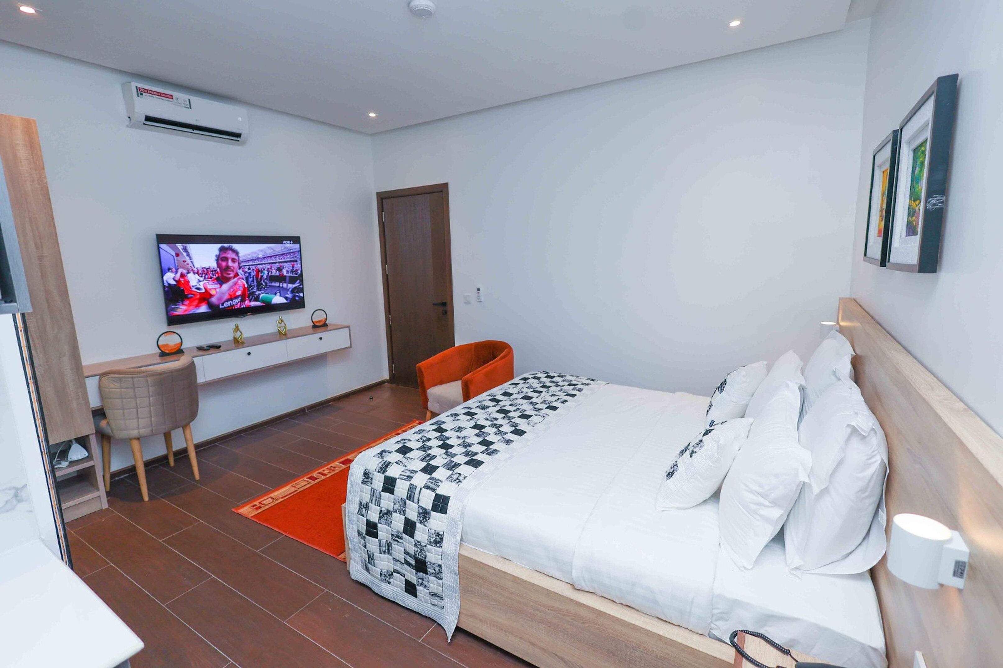 Una habitación de hotel moderna con una cama grande, un escritorio con una silla, un televisor y una mesita.