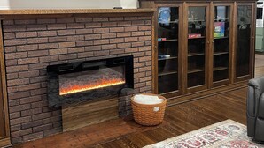 Een woonkamer met een open haard, een flatscreen televisie en decoratieve wanddecoratie.