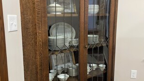 Een houten kast met glazen deuren, gevuld met gestapelde borden en kommen.