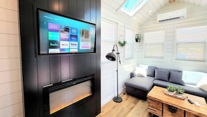 A modern living room with a mounted TV displaying various streaming services, a fireplace, a sofa, and a wooden coffee table. - Private Hot Tub + Rooftop Deck • Near Zion National Park (Apple Valley)