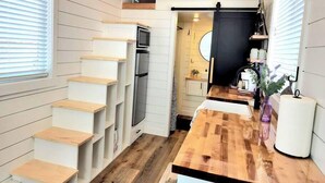 A compact kitchen with a wooden staircase, a built-in oven, and a dining area with a wooden table. - Private Hot Tub + Rooftop Deck • Near Zion National Park (Apple Valley)