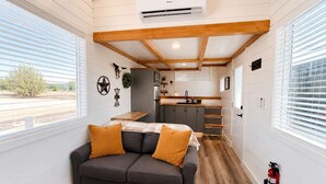 A compact living space with a sofa, kitchenette, and a fire extinguisher. - Zion Couples’ Retreat • Romantic Desert Tiny Home (Apple Valley)