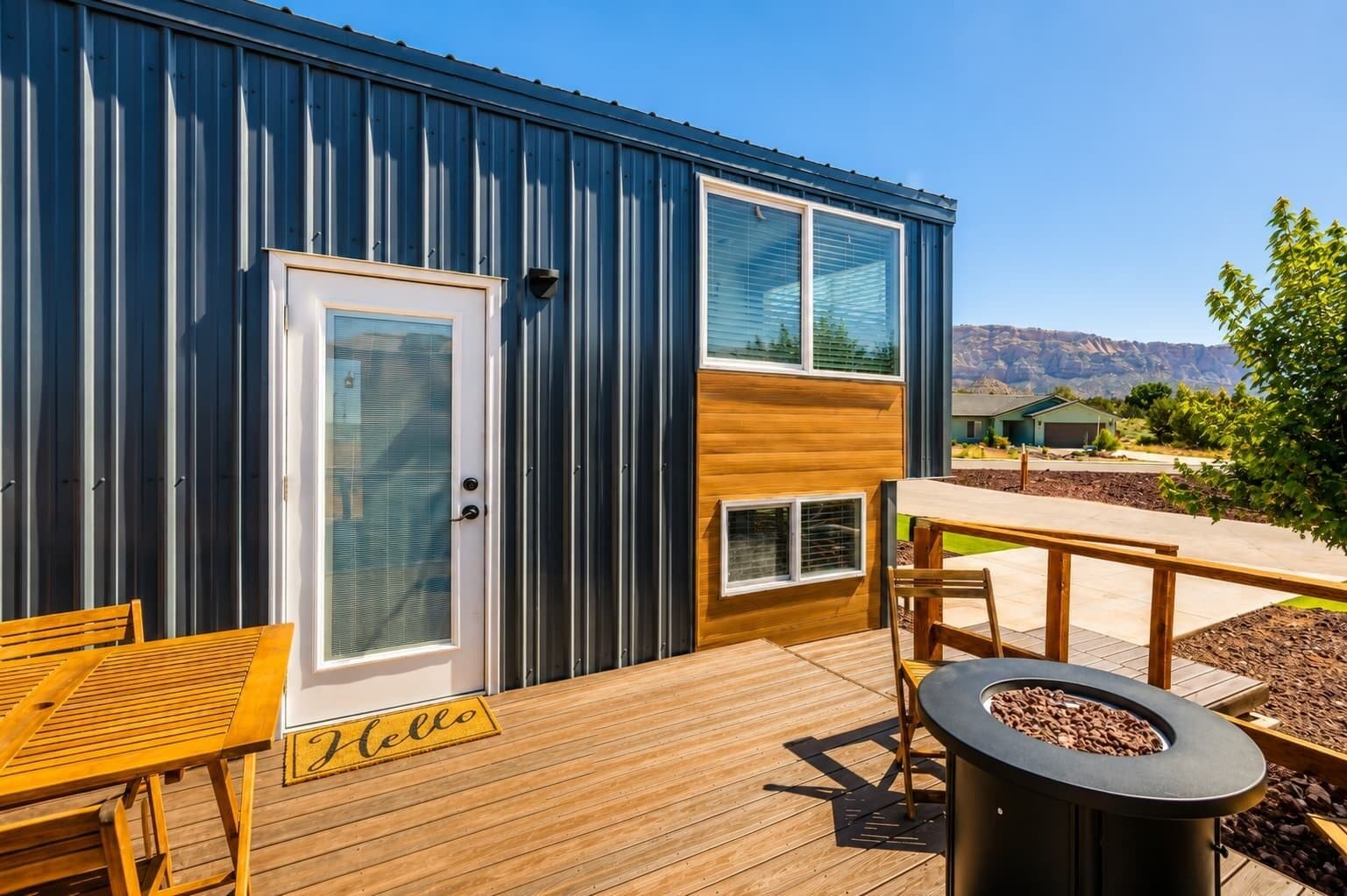 A modern building with a deck, a fire pit, and a bench.