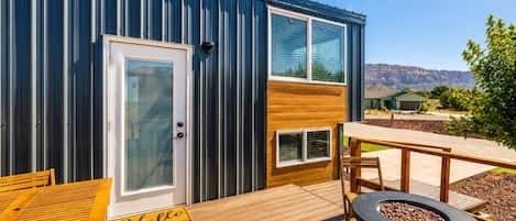 A modern building with a deck, a fire pit, and a bench.