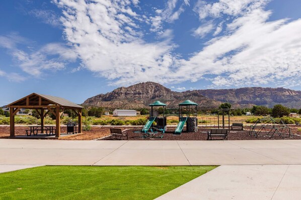 A park with a pavilion, picnic tables, a playground with slides, and a mountain in the background. - Family-Friendly Tiny Home • Firepit • BBQ • Zion (Apple Valley)