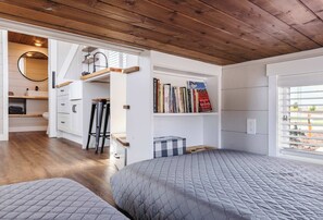 Ein Schlafzimmer mit einem großen Bett, einem Bücherregal, einem Schreibtisch und einem Fenster mit Jalousien.
