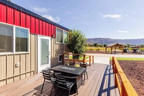 Eine Terrasse mit Tisch und Stühlen, eine Holzpergola und Blick auf Berge.