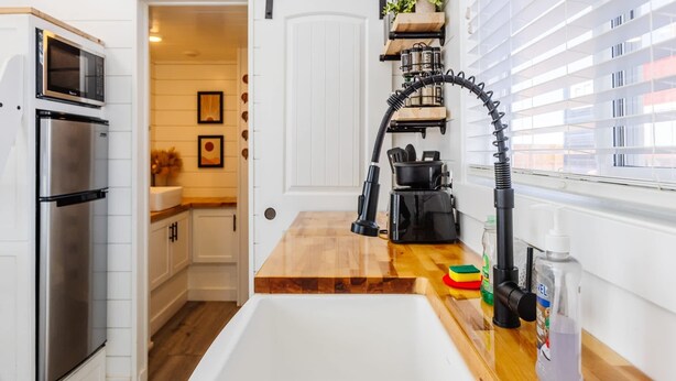 Una cocina con un refrigerador de acero inoxidable, una encimera de madera y un grifo negro.