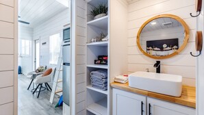 Un baño moderno con un tocador blanco, un espejo redondo y una encimera de madera.