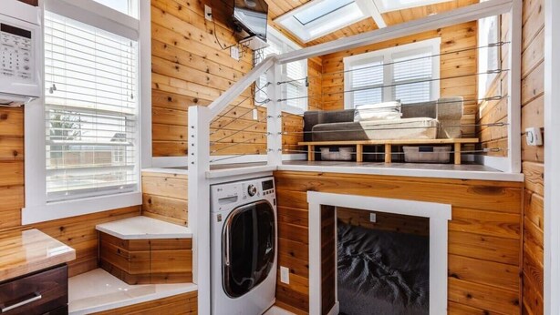 A compact, wood-paneled room with a washing machine, a sofa, and a small enclosed sleeping area. - Pet-Friendly Family Escape • Near Zion (Apple Valley)