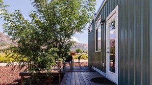 A modern building with a wooden deck, a door, and a view of a mountain range. - Pet-Friendly Family Escape • Near Zion (Apple Valley)