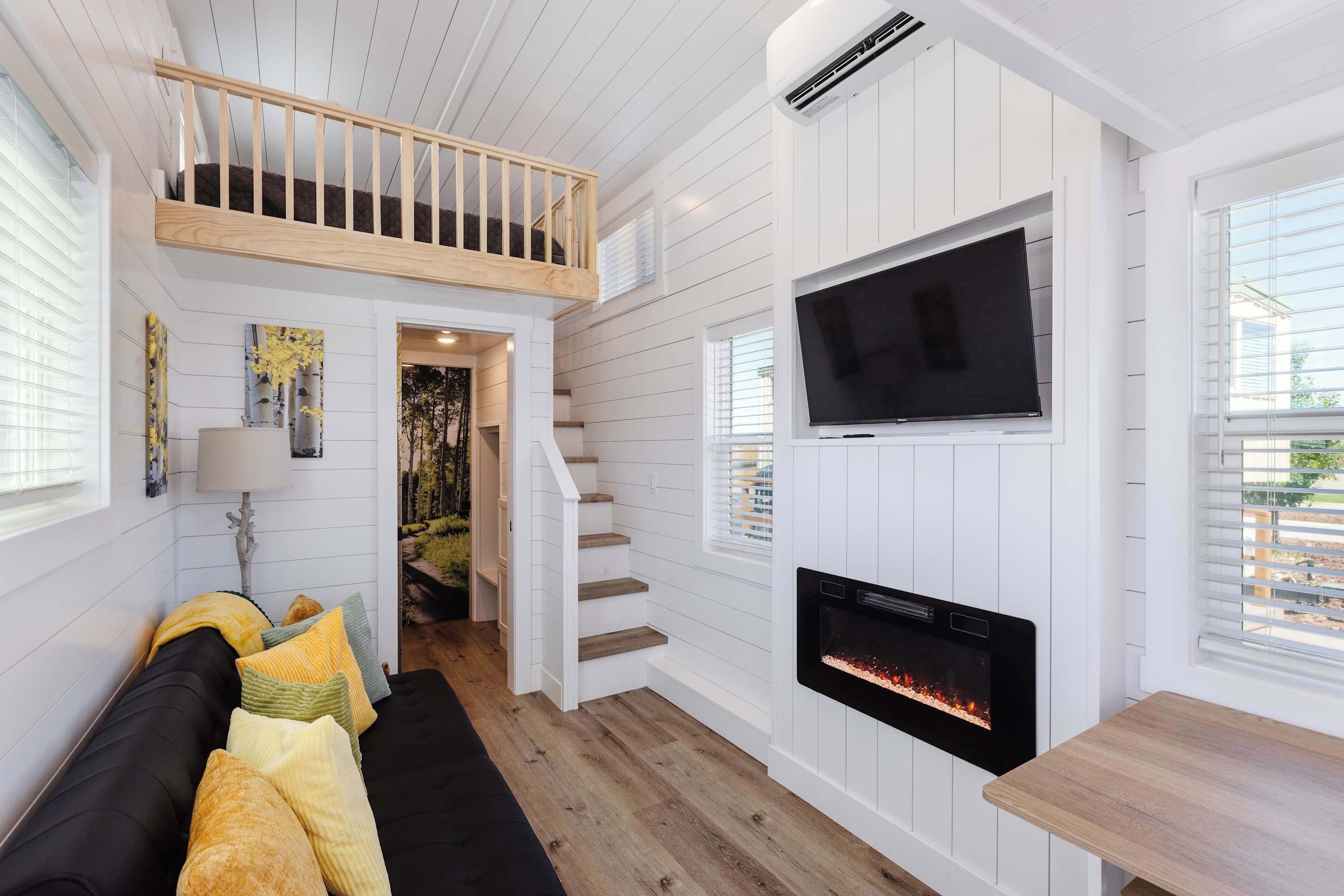A modern interior with a wooden staircase, a flat-screen TV, a fireplace, and a cozy seating area.