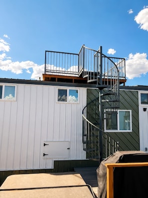 A building with a spiral staircase, a door, and a window. - Zion Basecamp • Hot Tub • Mountain Biking & Hiking (Apple Valley)