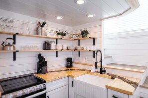 Una cocina moderna con armarios blancos, encimeras de madera y una estufa a gas integrada.