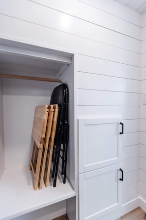 A white closet with a wooden bench and black chairs. - Zion Basecamp • Hot Tub • Mountain Biking & Hiking (Apple Valley)