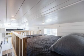A modern bedroom with a large bed, a wooden headboard, a small desk, and a window with blinds. - Zion Basecamp • Hot Tub • Mountain Biking & Hiking (Apple Valley)