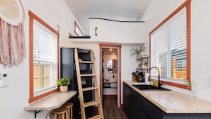 Una cocina compacta con una escalera de madera, taburetes y un pequeño comedor.