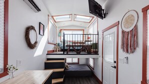 Una habitación pequeña y luminosa con literas, tragaluces, un comedor pequeño y un ambiente acogedor.