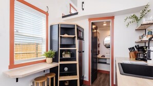 Una cocina compacta con horno integrado, una barra de madera y un pequeño rincón con taburetes.