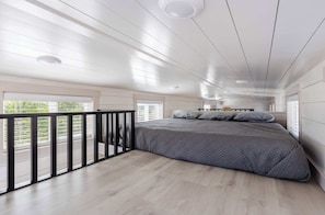 A spacious bedroom with a large bed, a balcony, and a view of greenery outside. - Pet-Friendly Zion Group Getaway (Apple Valley)