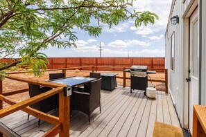 A wooden deck with outdoor furniture, a barbecue grill, and a fenced area. - Pet-Friendly Zion Group Getaway (Apple Valley)