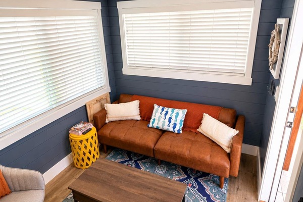 Cozy living area with a leather sofa, decorative pillows, and coffee table. Large windows bring in natural light, creating a bright space to relax after exploring Southern Utah and nearby outdoor adventures.