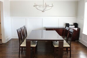 A dining area with a rectangular table, six chairs, a chandelier, and a small side table with speakers. - 2027 Augusta Masters Week Luxury Rental, 7 Miles from Augusta National Golf Club (Martinez)