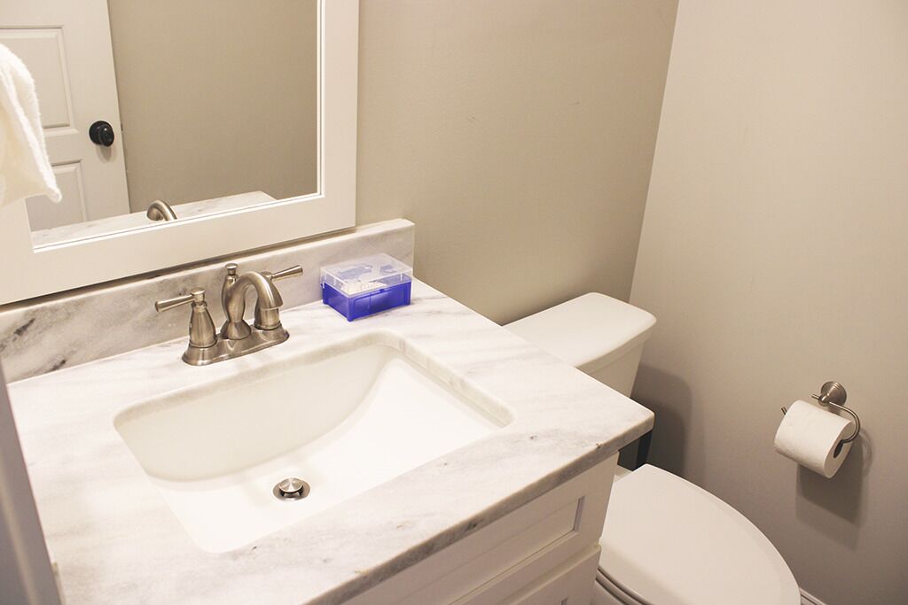 A bathroom with a marble sink, a toilet, and a mirror.