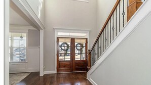 A hallway with wooden flooring, a white door with glass panels, and a staircase with a wooden railing. - 2027 Augusta Masters Week Luxury Rental, 7 Miles from Augusta National Golf Club (Martinez)