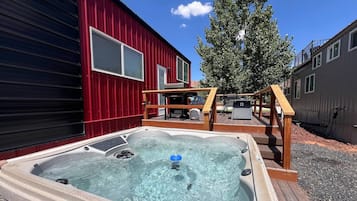A hot tub in a backyard with a red building and a tree.