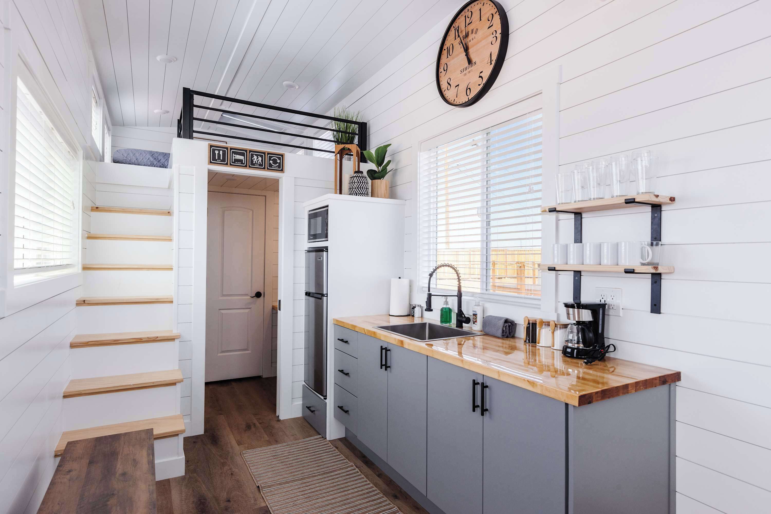 A modern kitchen with a wooden countertop, a built-in oven, and a clock on the wall.