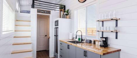 A modern kitchen with a wooden countertop, a built-in oven, and a clock on the wall.
