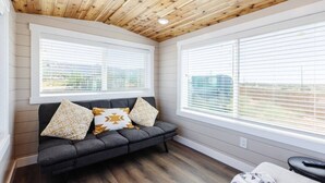 A cozy room with a dark grey sofa, two patterned pillows, and a wooden ceiling. - Zion Adventure • Private Hot Tub + Starry Nights (Apple Valley)